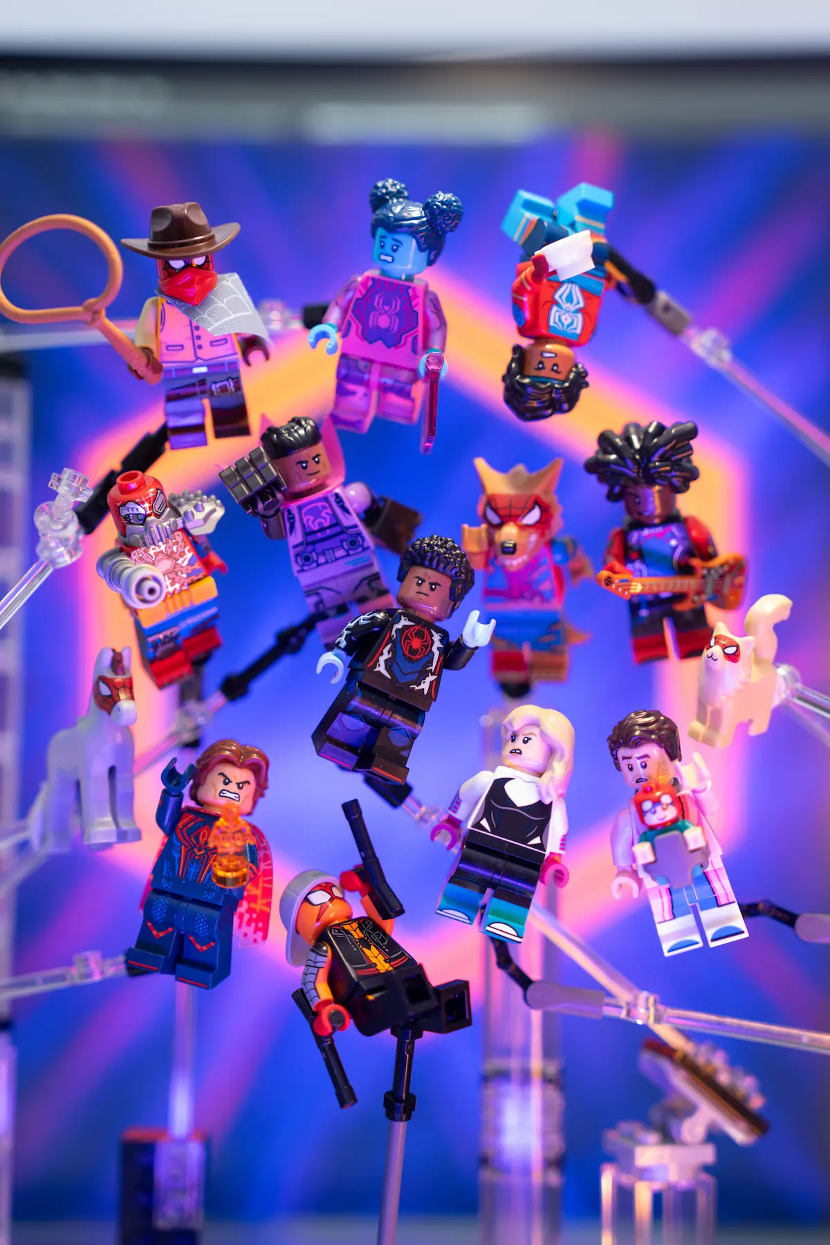 A group of LEGO minifigures posed as if floating mid-air, arranged in a circular formation against a vibrant purple and blue background with dynamic lighting and motion effects.