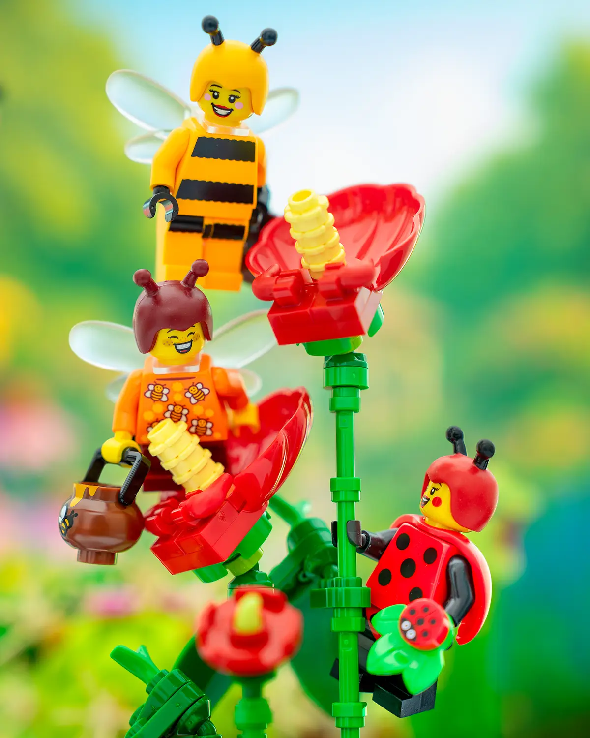LEGO bee and ladybug minifigures perch on bright red brick-built flowers in a colorful garden.