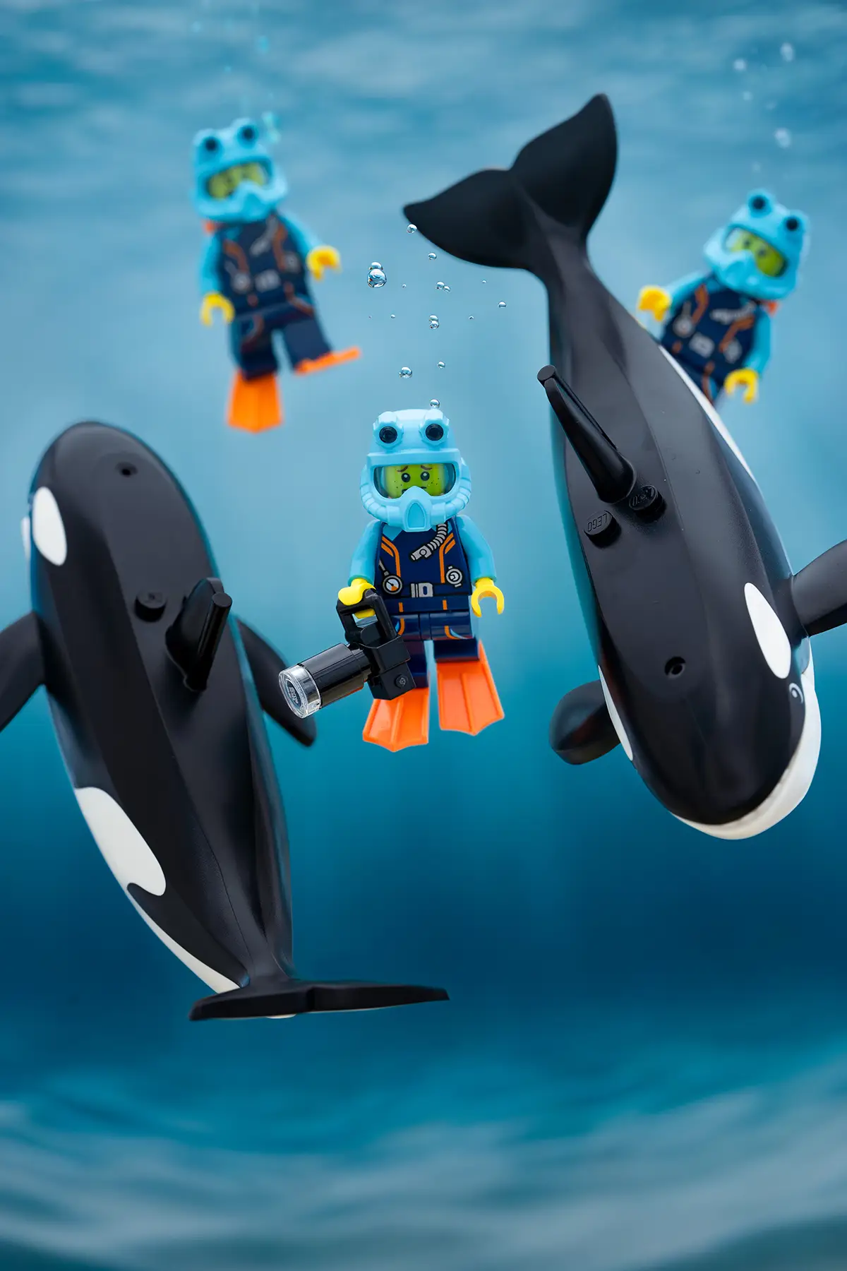 LEGO scuba divers exploring underwater alongside two orcas in a calm blue ocean