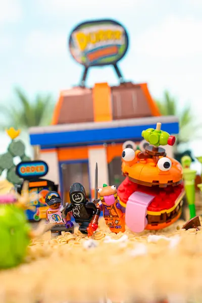 LEGO Fortnite minifigures pose in front of the Durrr Burger restaurant with the giant burger mascot behind them.