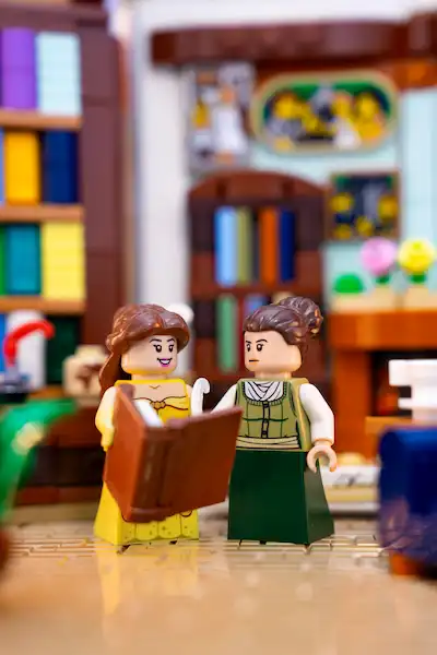 LEGO Belle and Jane Austen sharing a book in a cozy library setting.