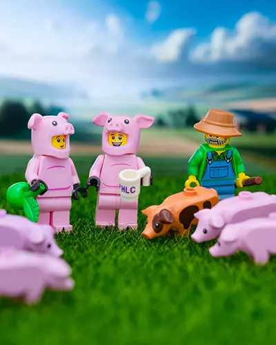 LEGO farmer and costumed pig characters surrounded by piglets on a bright, grassy farm.