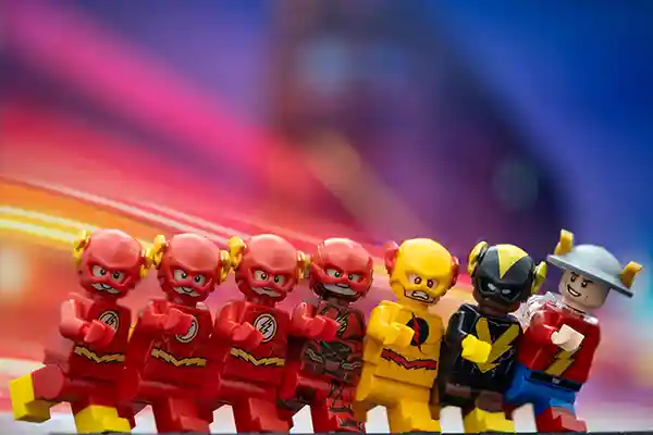 LEGO minifigures of various versions of The Flash and other speedsters, including Reverse Flash, Kid Flash, and Jay Garrick, posed in a running stance against a motion-blurred lightning background.