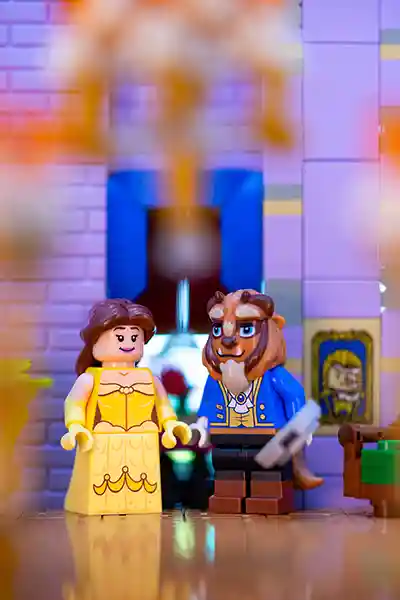 LEGO minifigures of Belle and the Beast sharing a moment in a ballroom-inspired LEGO scene.