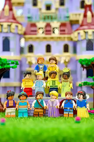 LEGO Disney royal characters gathered for a formal portrait with trees and a fantasy castle in the background.