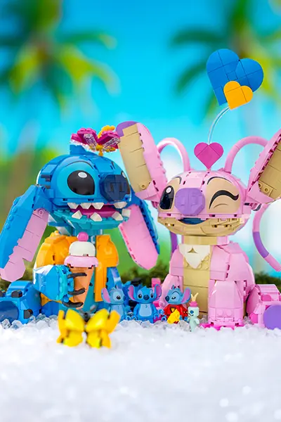 LEGO Stitch and Angel figures share a moment on a tropical beach surrounded by tiny Stitch minifigs and butterflies.