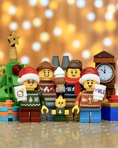LEGO family minifigures in festive Christmas sweaters posing in front of a tree and clock.