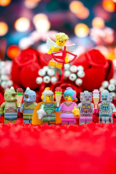 LEGO Cupid aims a heart arrow at alien, robot, and space-themed minifig couples
