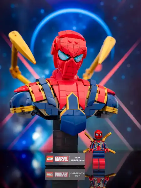 LEGO Marvel Iron Spider-Man bust on a display stand with a small Iron Spider minifigure beside it, set against a blue, glowing background.
