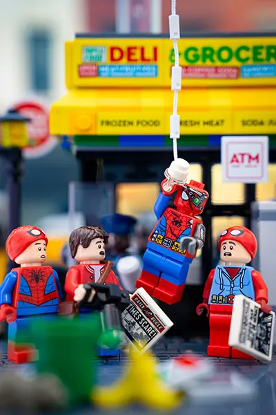 Cyborg Spider-Man swings past a Daily Bugle news scene in front of a LEGO grocery store
