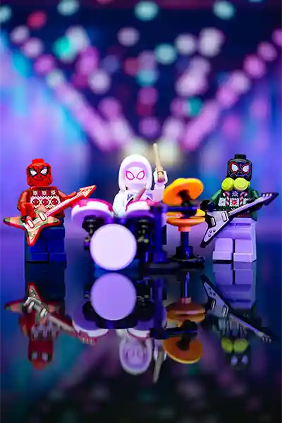LEGO minifigures of Spider-Man, Spider-Gwen, and Miles Morales performing as a festive band under colorful lights.