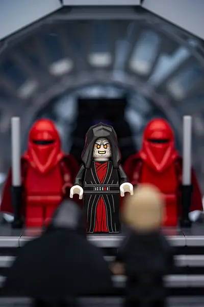 LEGO Emperor Palpatine faces off against two Jedi minifigures holding lightsabers in his throne room.